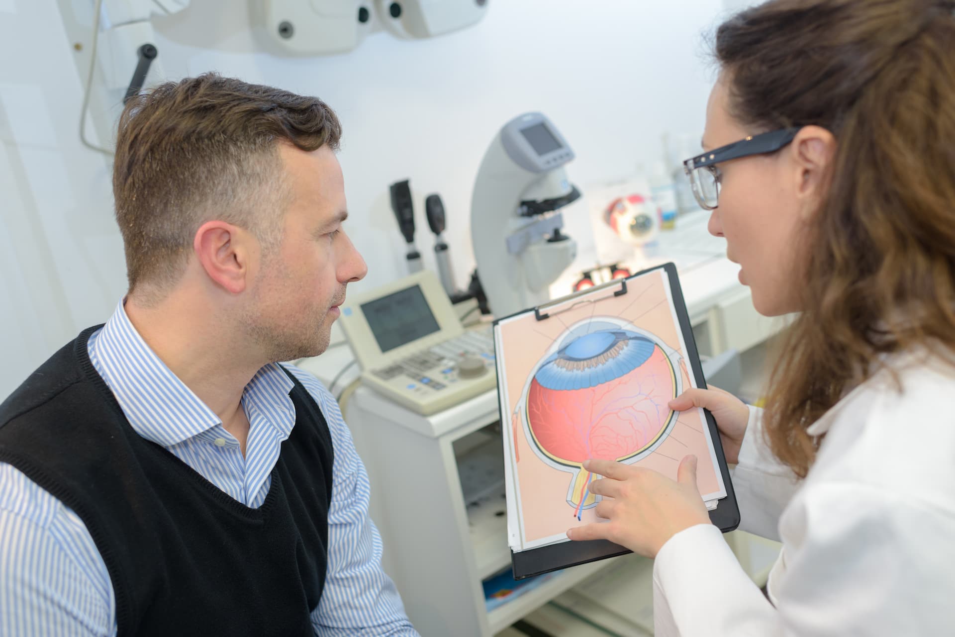 Optometrist talking with a patient about glaucoma while pointing to an eye chart