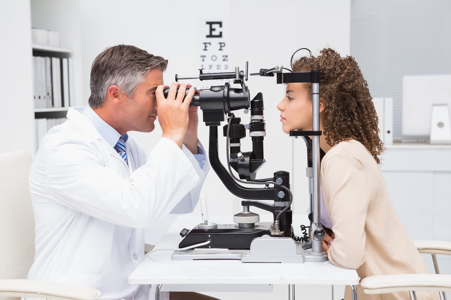 Optometrist examining a patient's eyes with a slit lamp for glaucoma treatment